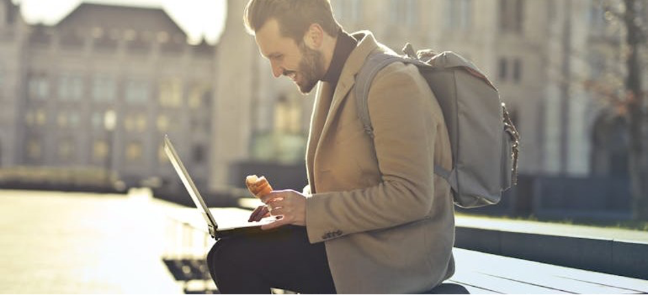 a man with a backpack and a laptop choosing between digital nomad visas vs. traditional work permits